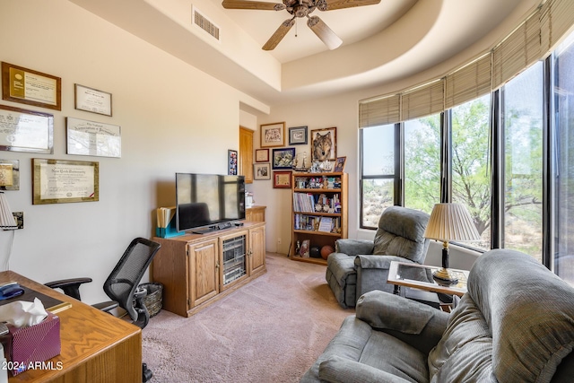 carpeted office featuring a raised ceiling and ceiling fan