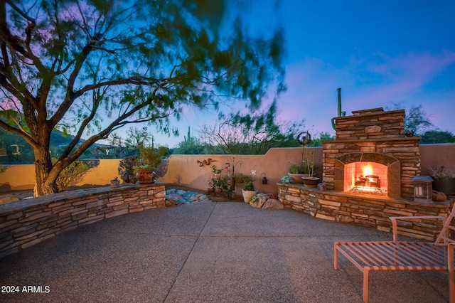 patio terrace at dusk with an outdoor stone fireplace