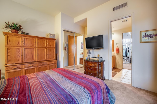 bedroom featuring ensuite bath, light colored carpet, and a closet