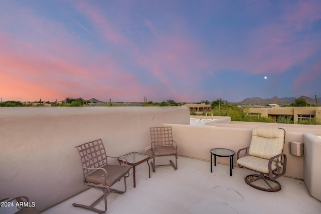 patio terrace at dusk with a mountain view and a balcony