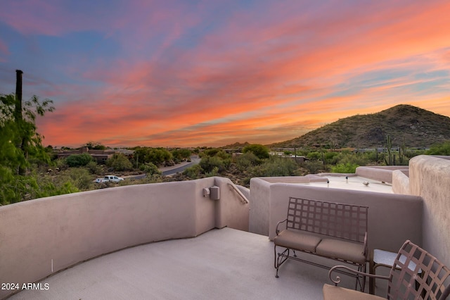 patio terrace at dusk featuring a mountain view and a balcony