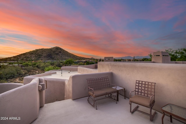 patio terrace at dusk with a mountain view and a balcony