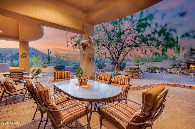 patio terrace at dusk featuring a mountain view and an outdoor stone fireplace