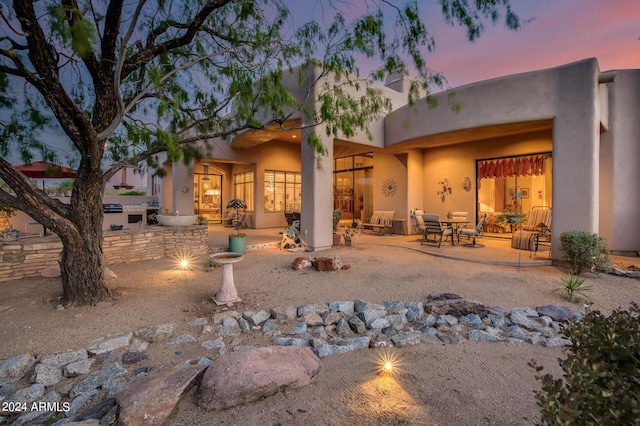 back house at dusk with a patio area