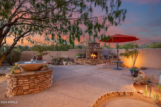 patio terrace at dusk with an outdoor stone fireplace