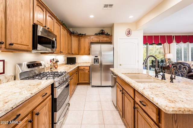 kitchen with light tile patterned floors, visible vents, appliances with stainless steel finishes, brown cabinets, and a sink