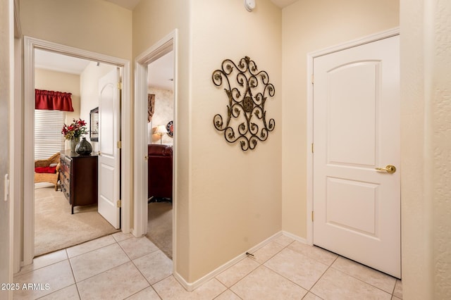 hall with light colored carpet, light tile patterned flooring, and baseboards