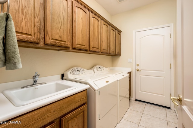 washroom featuring cabinet space, washing machine and dryer, light tile patterned floors, and a sink