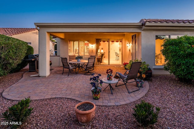 patio terrace at dusk featuring a grill