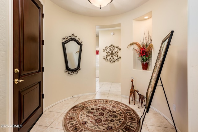 hall featuring light tile patterned floors and baseboards