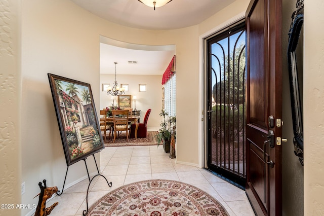 entrance foyer featuring baseboards, visible vents, an inviting chandelier, and light tile patterned floors