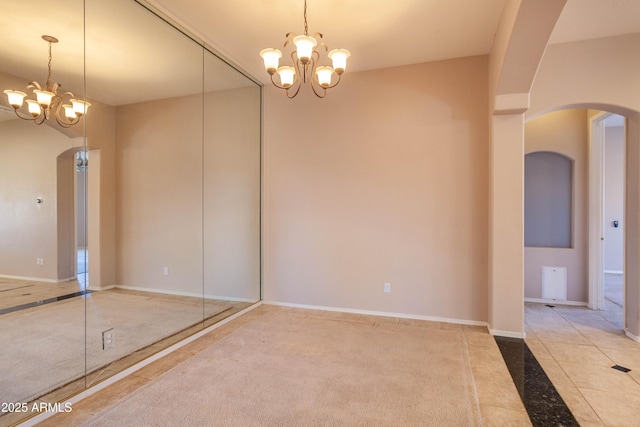 carpeted empty room with a chandelier