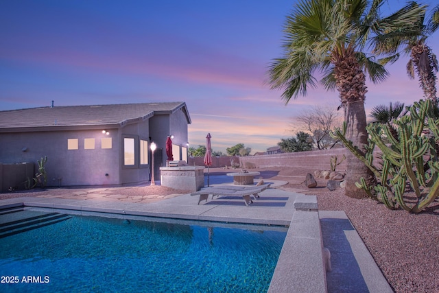 pool at dusk featuring a patio