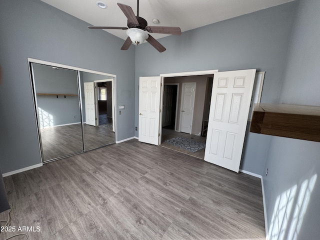 unfurnished bedroom featuring dark hardwood / wood-style flooring, lofted ceiling, a closet, and ceiling fan