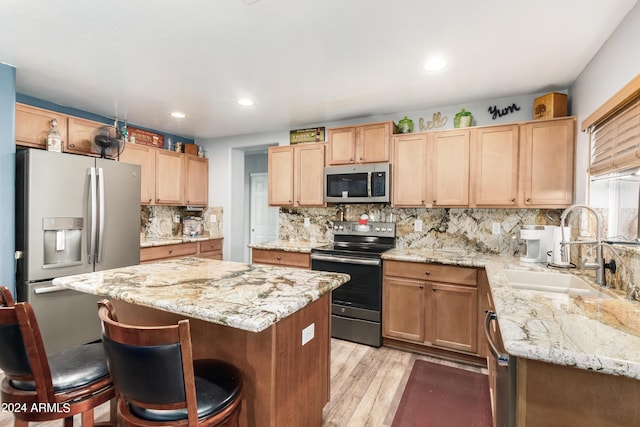 4321 E Morenci Rd, San Tan Valley, AZ 85143 - kitchen with appliances with stainless steel finishes, a sink, a kitchen breakfast bar, light wood-style flooring, and a kitchen island
