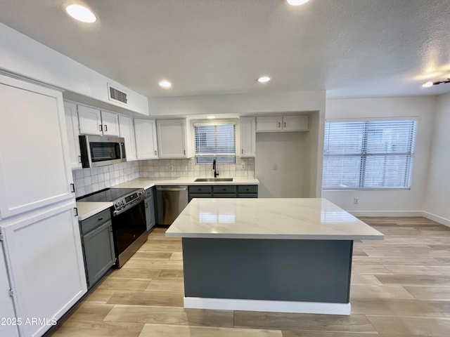 kitchen with a kitchen island, tasteful backsplash, appliances with stainless steel finishes, and sink