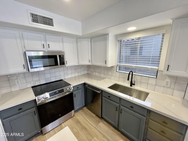 kitchen featuring white cabinetry, appliances with stainless steel finishes, gray cabinets, and sink