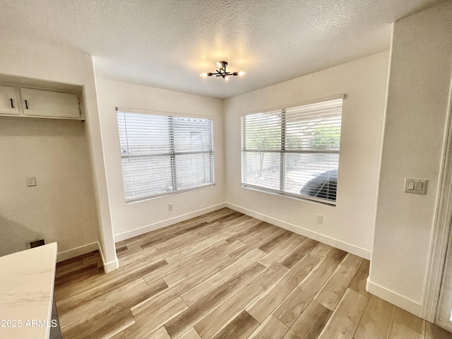 unfurnished dining area with light hardwood / wood-style floors and a textured ceiling