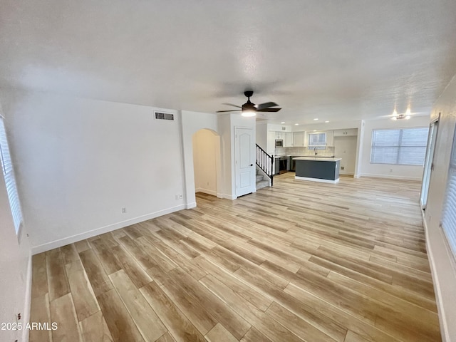 unfurnished living room featuring ceiling fan, sink, and light hardwood / wood-style floors