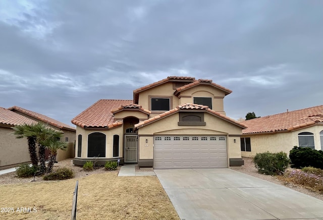 mediterranean / spanish home with concrete driveway, a tiled roof, and stucco siding