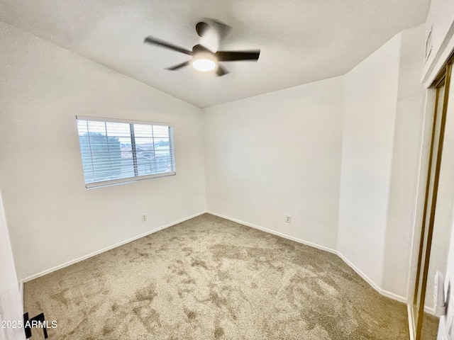 spare room with vaulted ceiling, carpet, and ceiling fan