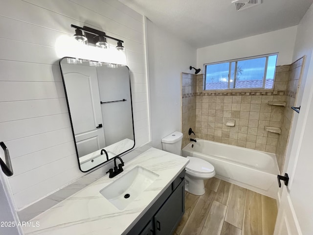 full bathroom featuring tiled shower / bath, wood-type flooring, vanity, and toilet