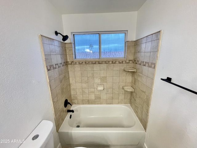 bathroom with toilet and tiled shower / bath