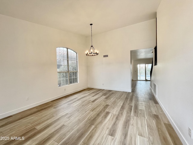 unfurnished dining area with light wood-type flooring, an inviting chandelier, baseboards, and visible vents