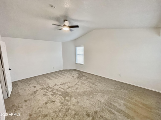 spare room with a textured ceiling, carpet floors, ceiling fan, and vaulted ceiling