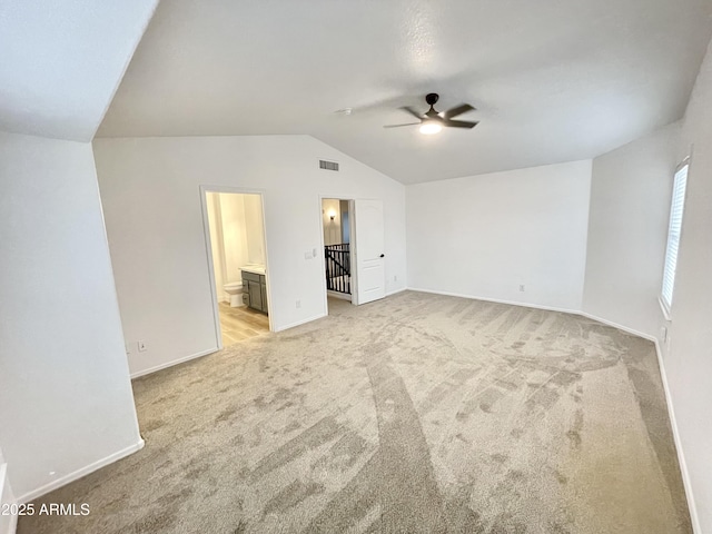 unfurnished bedroom with light carpet, ensuite bath, vaulted ceiling, and ceiling fan