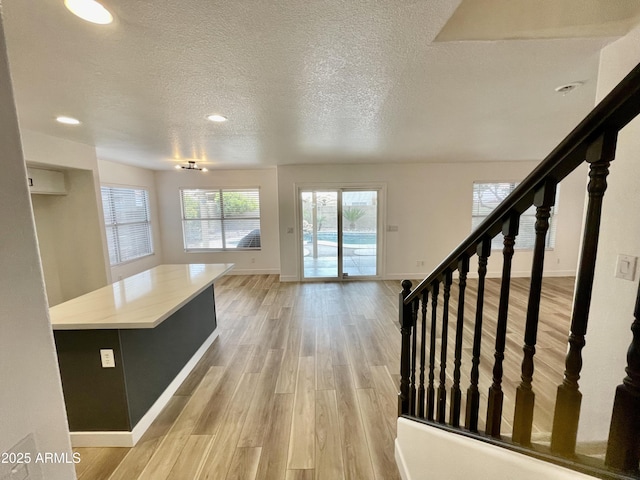 unfurnished living room featuring a textured ceiling and light hardwood / wood-style floors