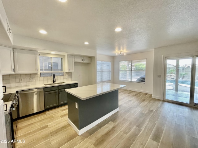 kitchen with sink, dishwasher, tasteful backsplash, light hardwood / wood-style floors, and a kitchen island