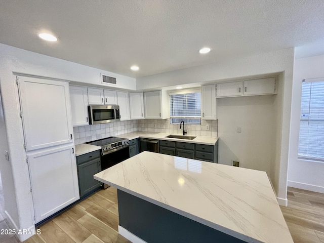 kitchen featuring appliances with stainless steel finishes, gray cabinets, sink, and light hardwood / wood-style flooring