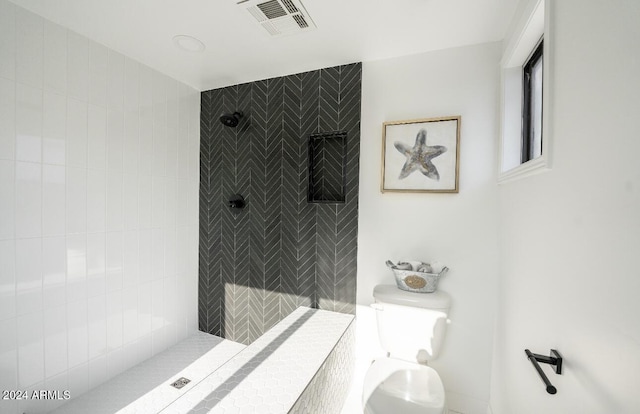 bathroom featuring tiled shower and toilet