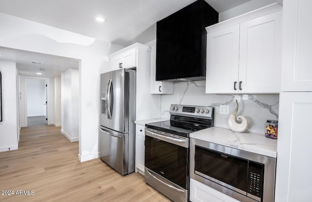 kitchen with light stone countertops, white cabinetry, light hardwood / wood-style flooring, and stainless steel appliances