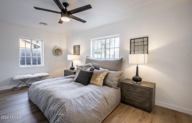 bedroom with dark hardwood / wood-style flooring, multiple windows, and ceiling fan