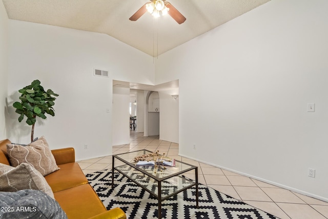 tiled living area featuring a ceiling fan, visible vents, vaulted ceiling, and baseboards