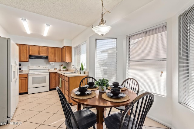 kitchen with light tile patterned floors, brown cabinetry, a sink, ventilation hood, and white appliances