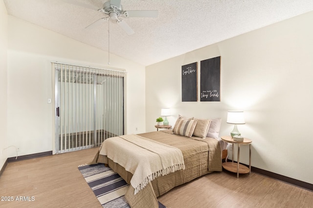 bedroom featuring lofted ceiling, a textured ceiling, wood finished floors, and baseboards