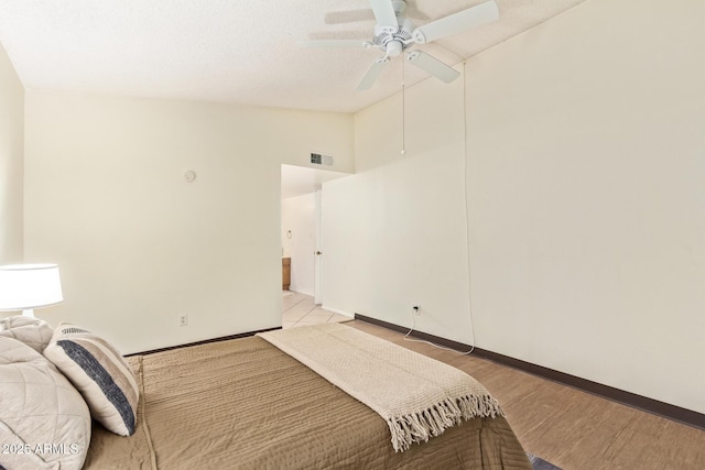 bedroom with light wood finished floors, baseboards, visible vents, ceiling fan, and vaulted ceiling