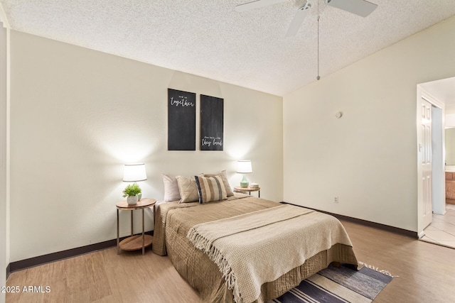 bedroom with ceiling fan, a textured ceiling, baseboards, and wood finished floors