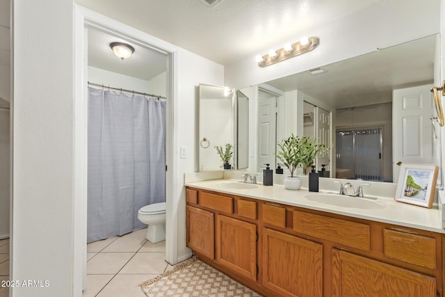 bathroom featuring double vanity, toilet, a sink, and tile patterned floors