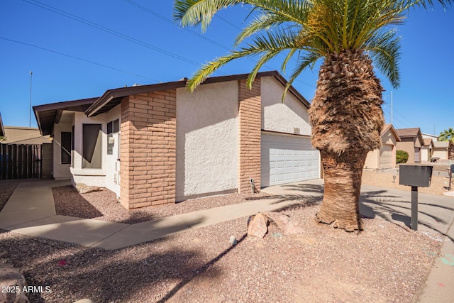 view of home's exterior featuring concrete driveway, brick siding, an attached garage, and stucco siding