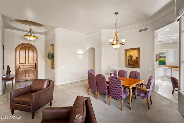 dining area with light tile patterned floors, crown molding, and a chandelier