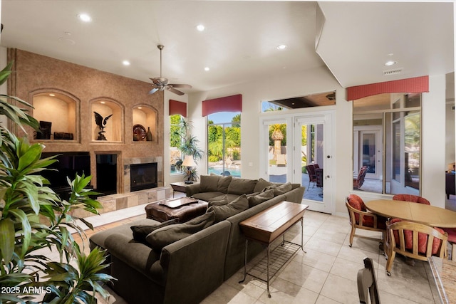 living room with ceiling fan, light tile patterned floors, and a tile fireplace