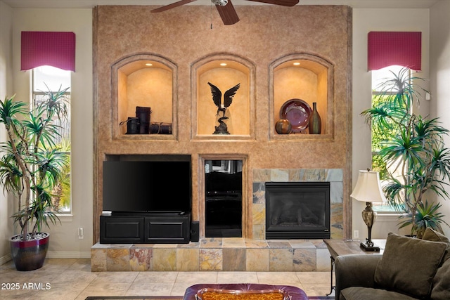 tiled living room with ceiling fan, a wealth of natural light, and a tile fireplace