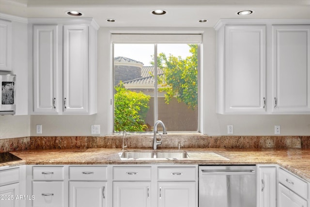 kitchen with appliances with stainless steel finishes, white cabinetry, light stone counters, and sink