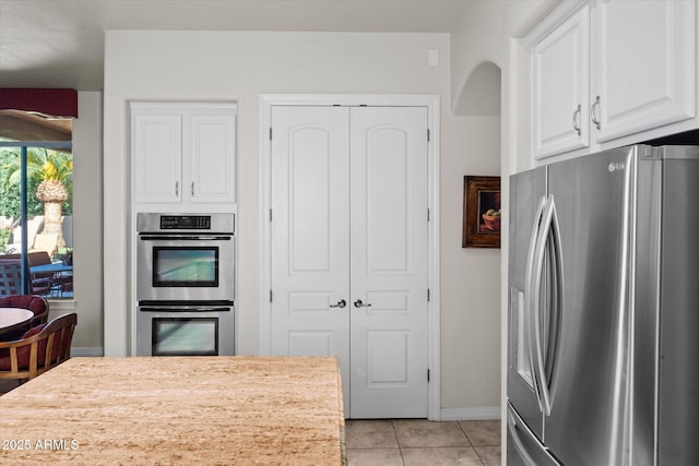 kitchen featuring light tile patterned flooring, stainless steel appliances, and white cabinetry