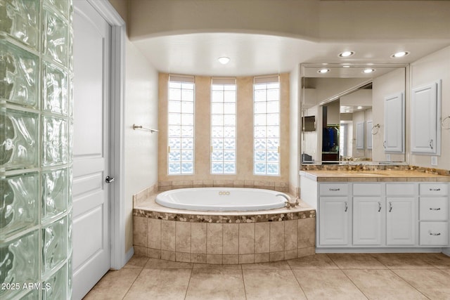 bathroom with tiled bath, tile patterned floors, and vanity