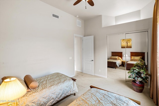 bedroom featuring a closet, light colored carpet, a high ceiling, and ceiling fan